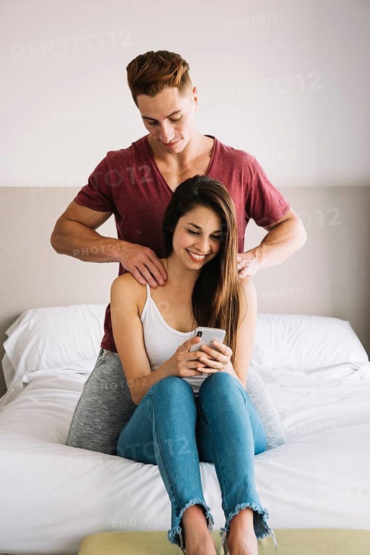 Man massaging shoulder woman bed
