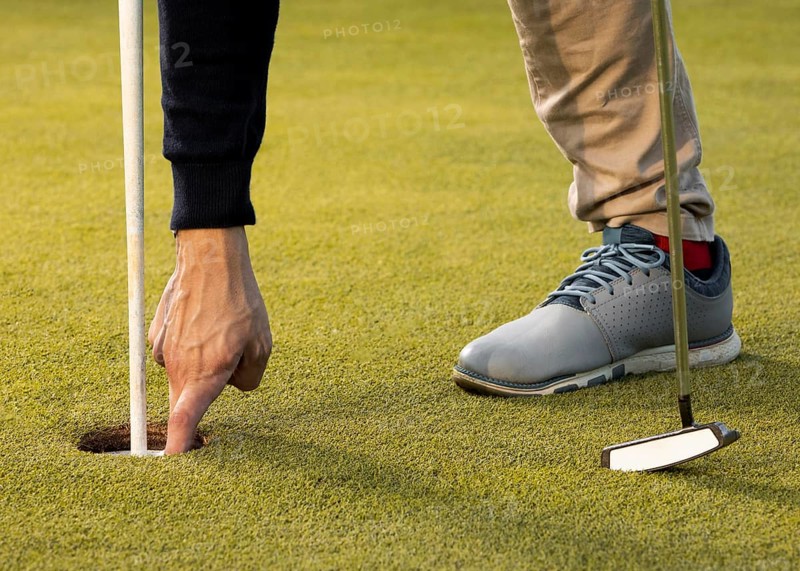 Man reaching into golf ball hole with hand
