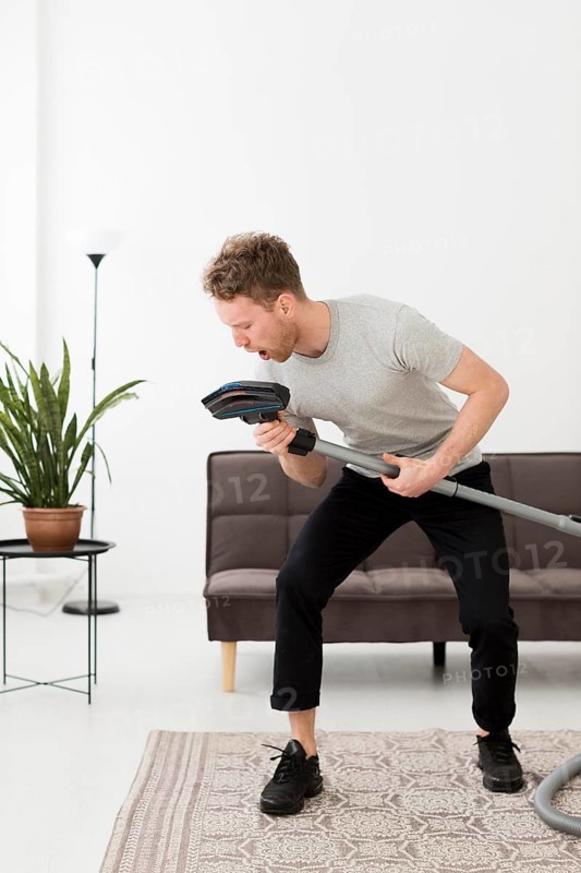 Man singing vacuum while cleaning
