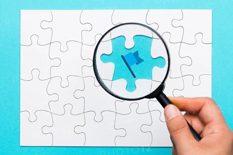 Person s hand holding magnifying glass flag icon blue backdrop