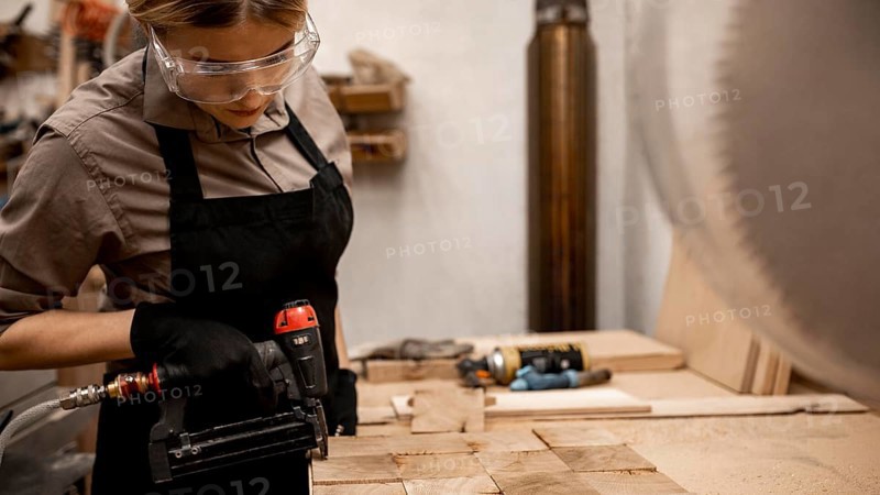 Side view female carpenter with pneumatic stapler