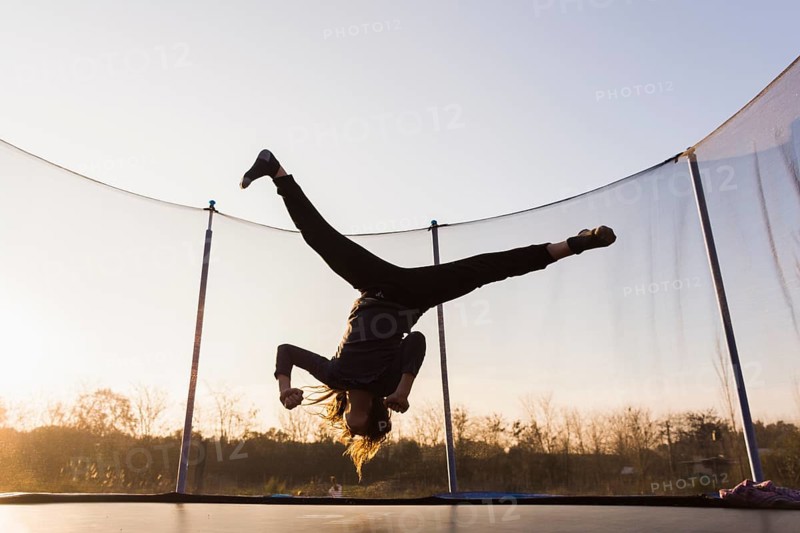 Silhouette girl jumping trampoline doing split
