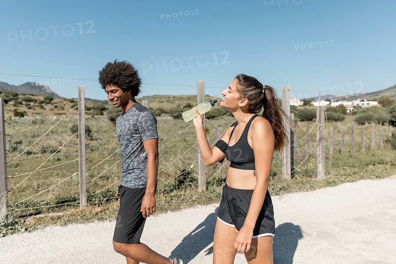 Smiling people walking while woman drinking water