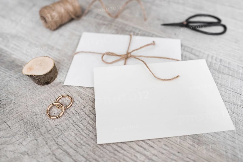 Spool miniature tree stump wedding rings scissor white envelope wooden background