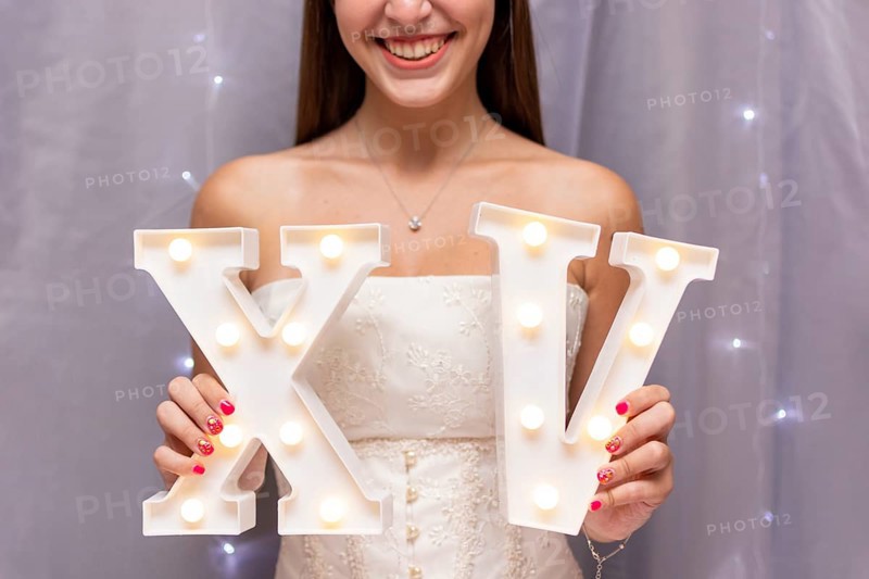 Teenage girl celebrating quinceanera while holding roman numerals