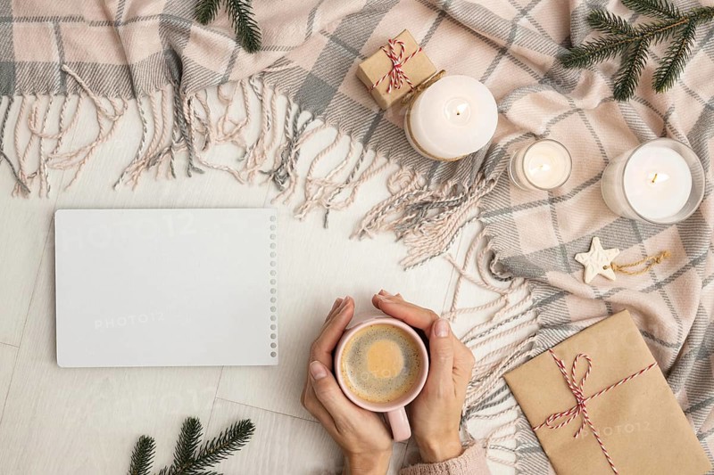 Top view person holding mug with blanket candles
