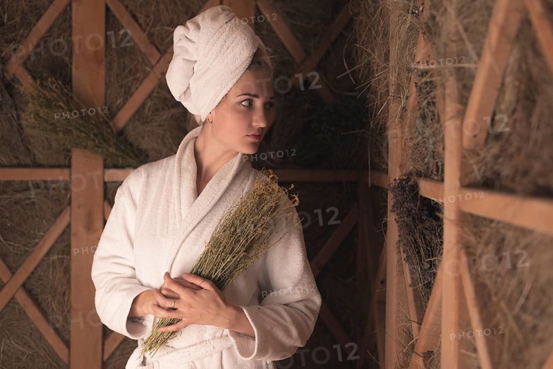 Young woman bathrobe holding medical herbs