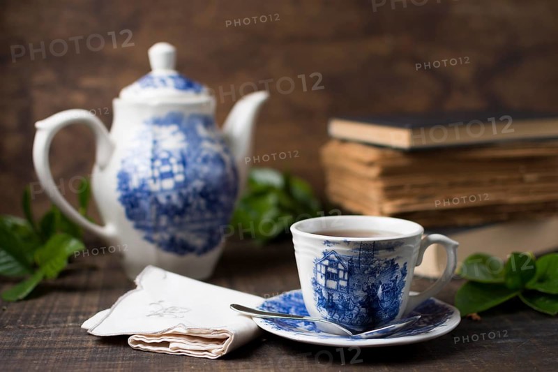 Antique porcelain tea cup teapot with books folded napkin wooden table