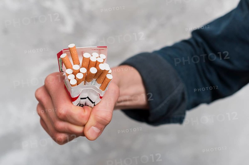 Close up man s hand crushing cigarettes box