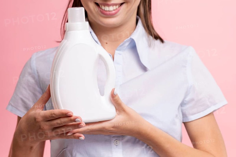 Close up smiley woman holding detergent bottle