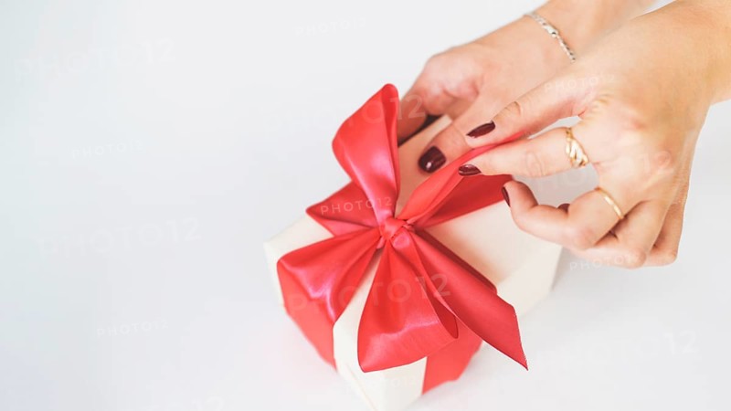 Close up woman s hand unwrapping gift box white background