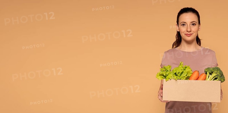 Copy space woman holding cartoon box with vegetables