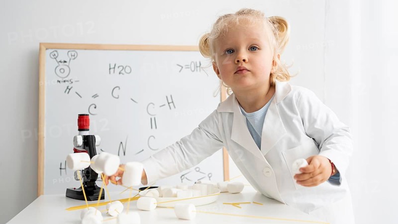 Cute toddler learning about science with whiteboard microscope
