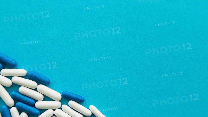 Elevated view white blue candy capsules corner cyan backdrop