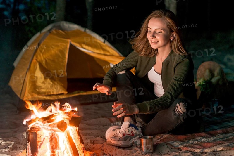 Girl warming up by campfire