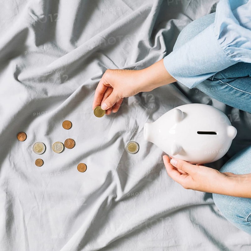 Human hand holding coins piggybank