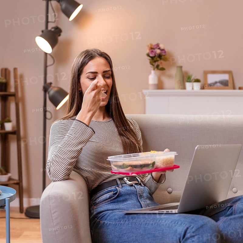 Hungry businesswoman eating sitting sofa