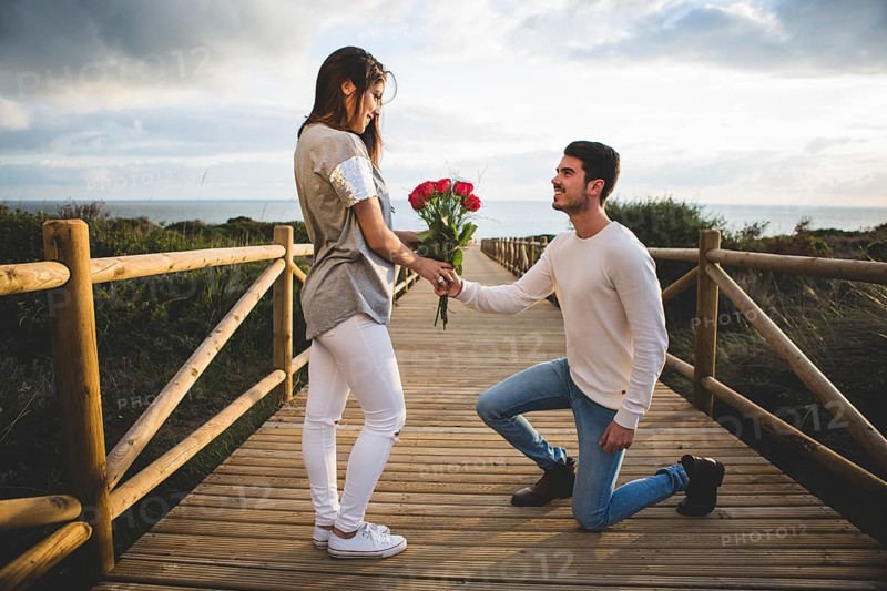 Man kneeling handing bouquet roses woman