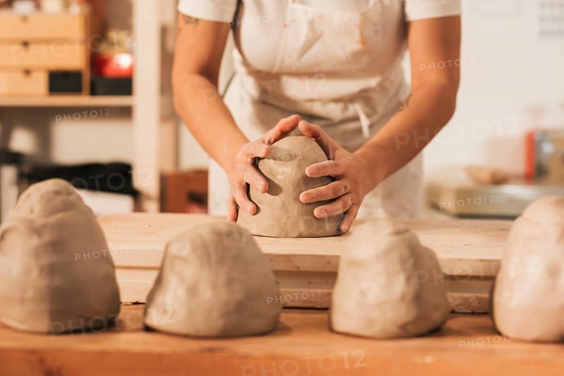 Midsection female craftswoman giving shape clay wooden table