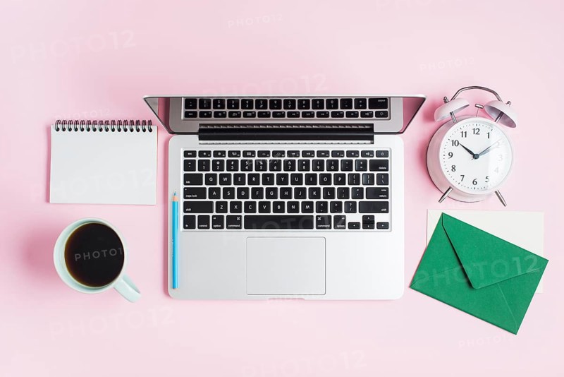 Open laptop pencil alarm clock spiral notepad envelope pink background