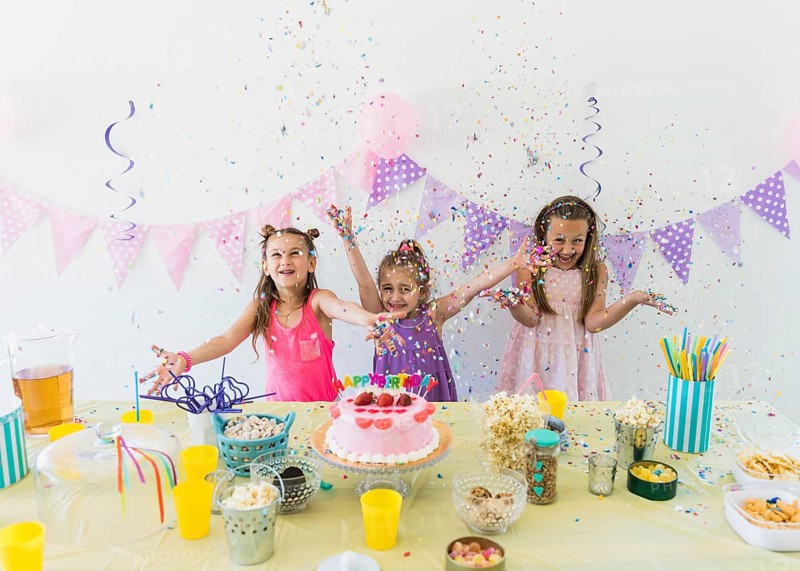 Pretty girls enjoying birthday party home with variety food juice table