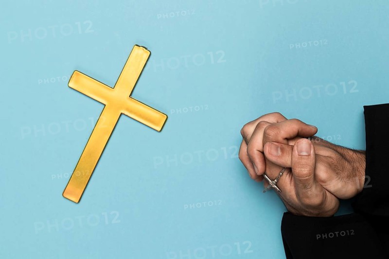 Priest praying with wood cross