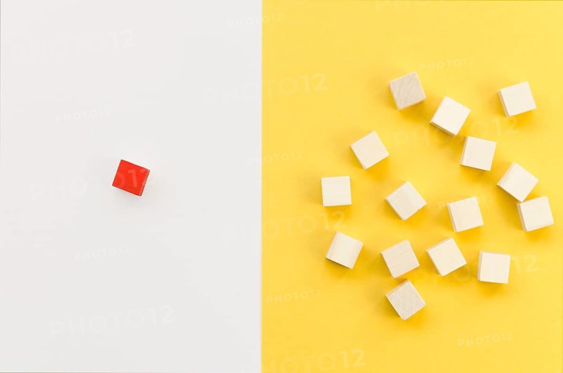 Red cube separated from group wooden ones