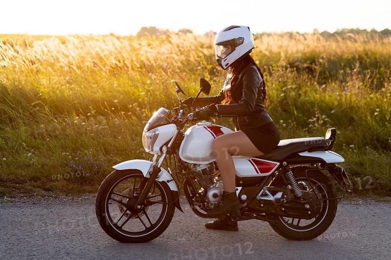 Side view woman riding motorcycle with helmet