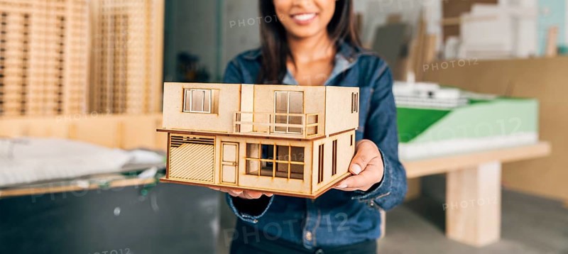Smiling african american woman showing model house
