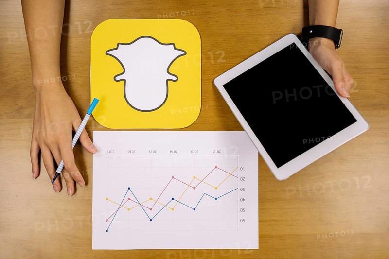 Social media planner analyzing snapchat graph with digital tablet