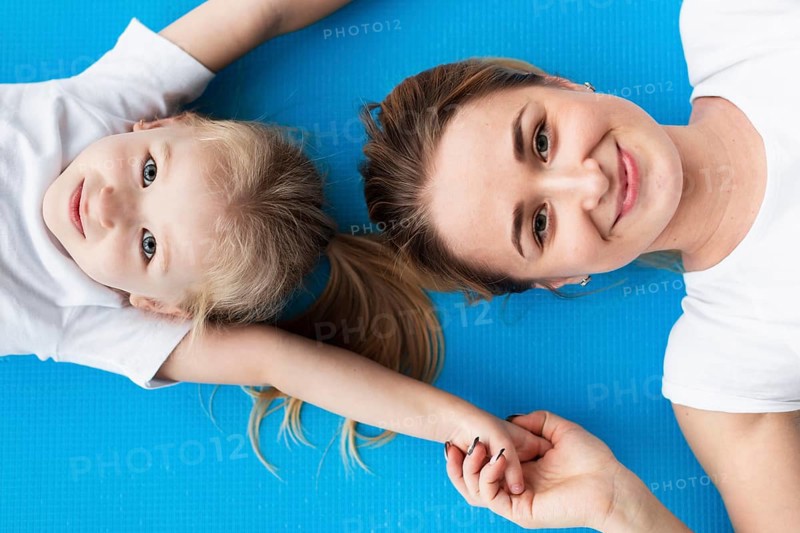 Top view happy mother posing with daughter yoga mat