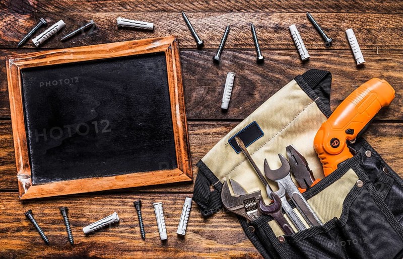 Various tools toolbag near blank slate bolts wooden background
