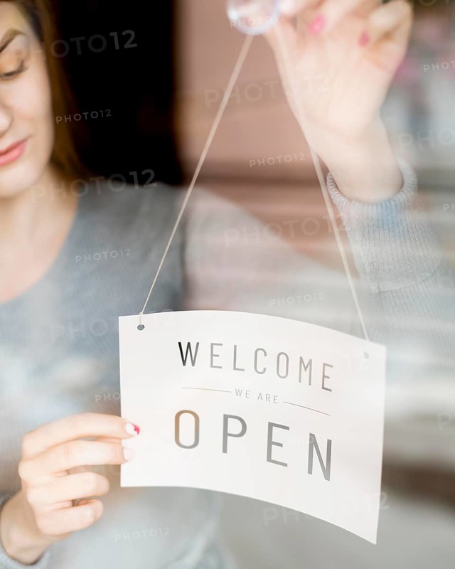 Woman putting open sign window coffee shop
