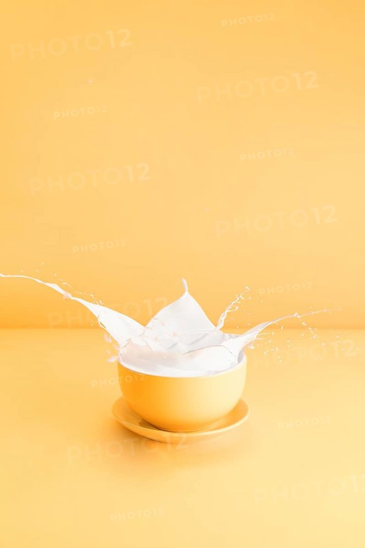 Yellow cup with spilling milk