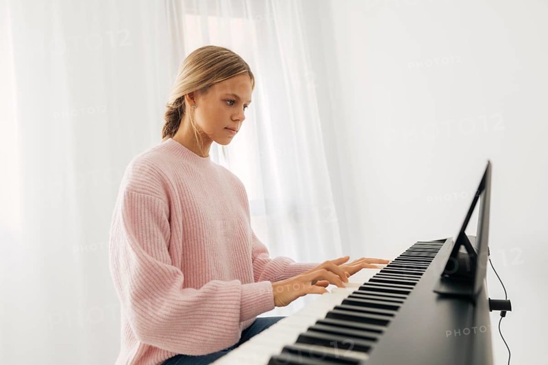 Young girl playing keyboard instrument home