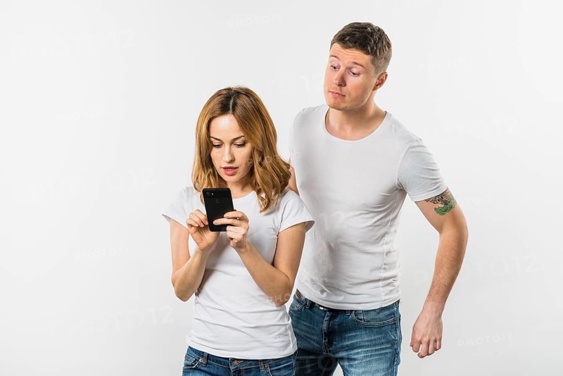 Young man trying spy her girlfriend s mobile phone isolated white background