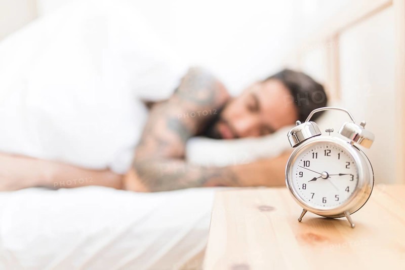 Alarm clock wooden desk with man sleeping background
