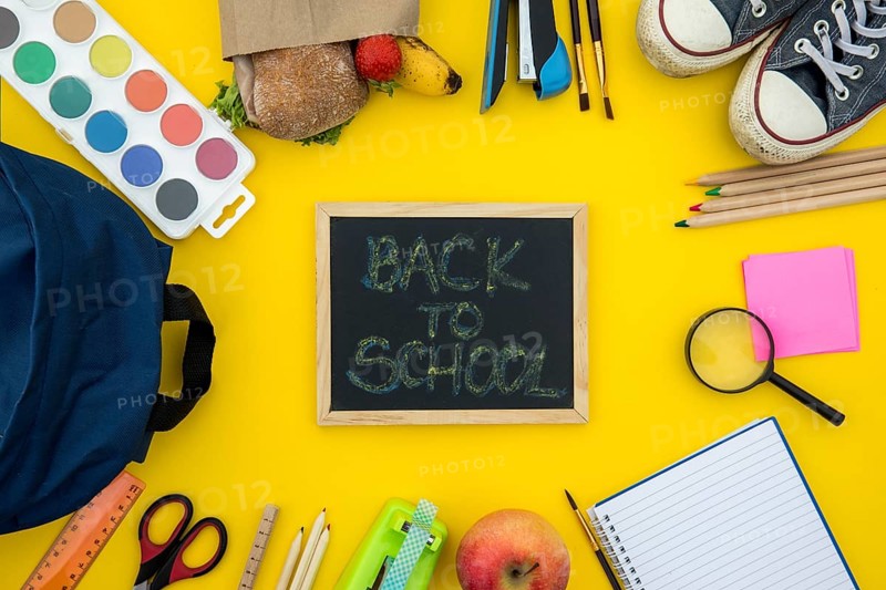 Blackboard with school accessories yellow background