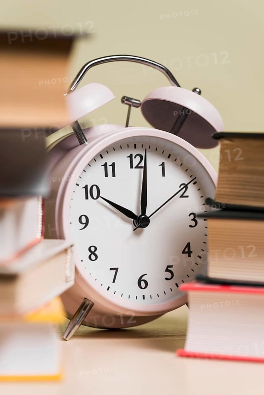 Close up alarm clock stacked books