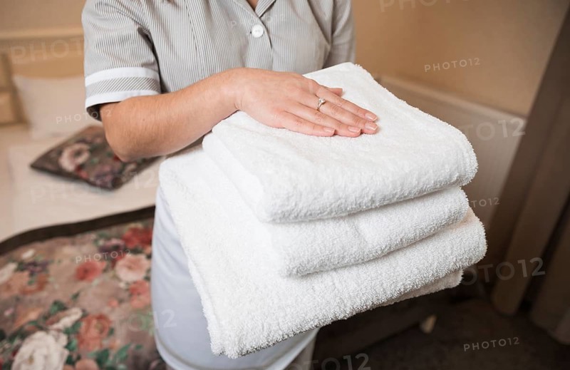 Close up female chambermaid holding clean soft folded towel hand