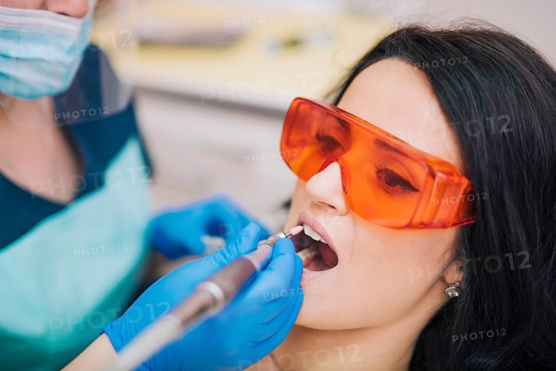 Dentist curing teeth patient glasses