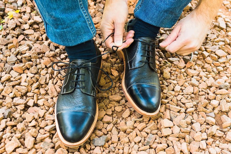 Elevated view man s foot pebble tying shoelace