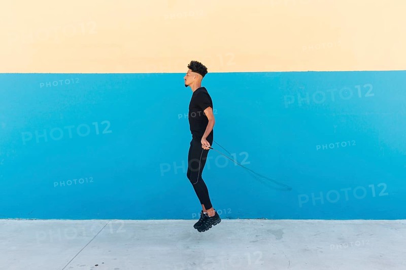 Ethnic man jumping rope street