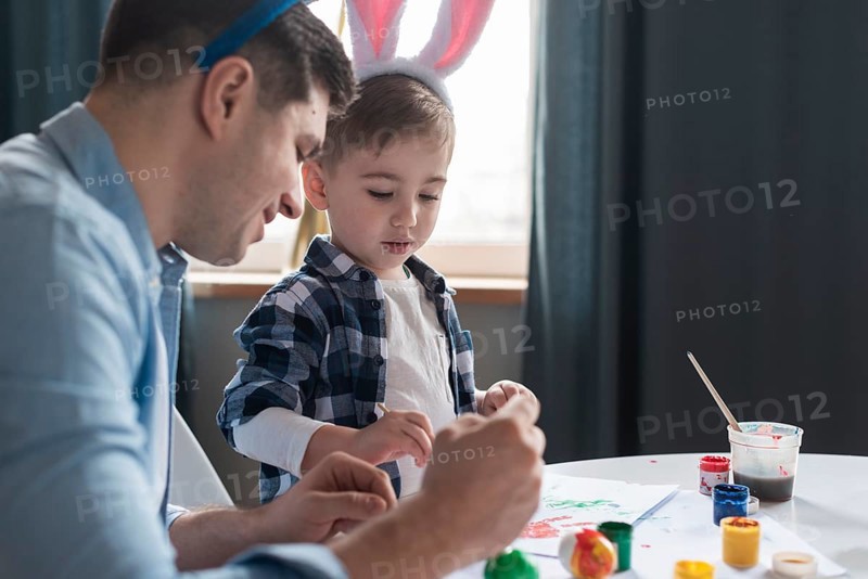 Father showing his son how paint easter eggs