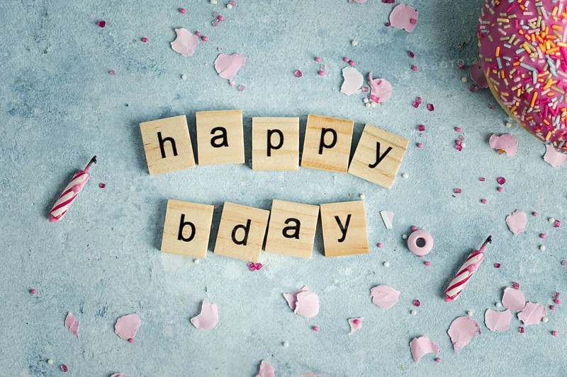 Flat lay happy birthday wish wooden letters with doughnut