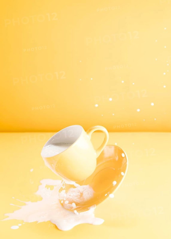 Floating yellow cup with spilling milk