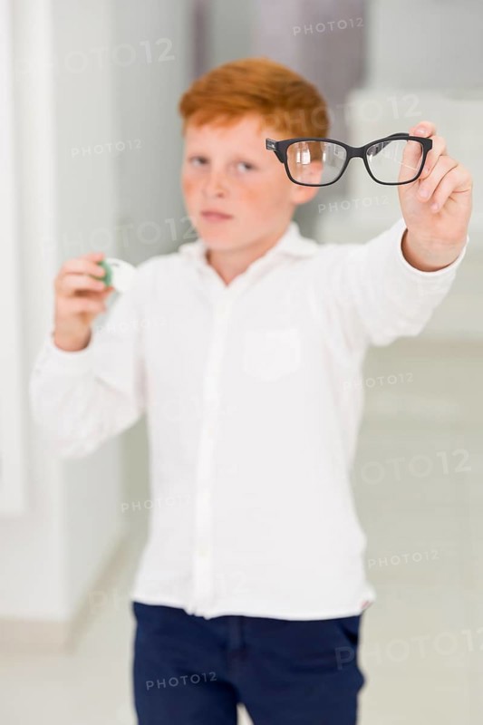 Freckle boy holding eyeglasses contact lenses container