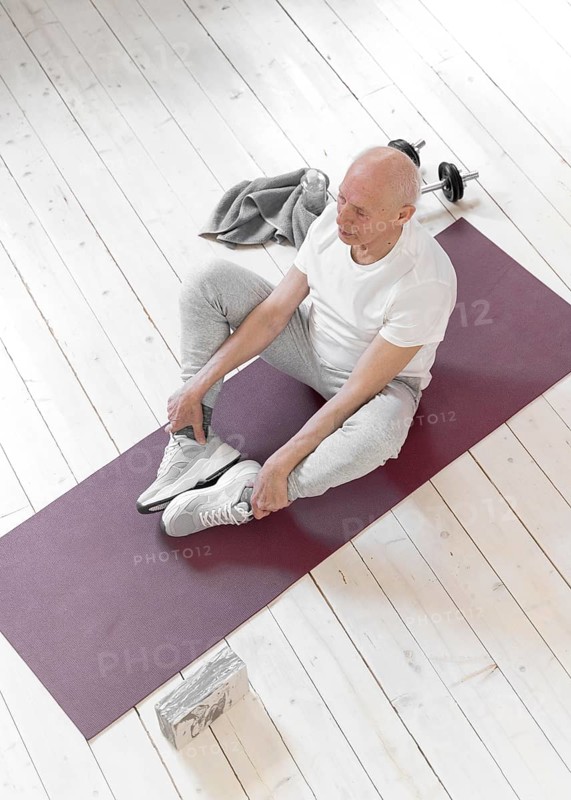 Full shot senior man sitting yoga mat