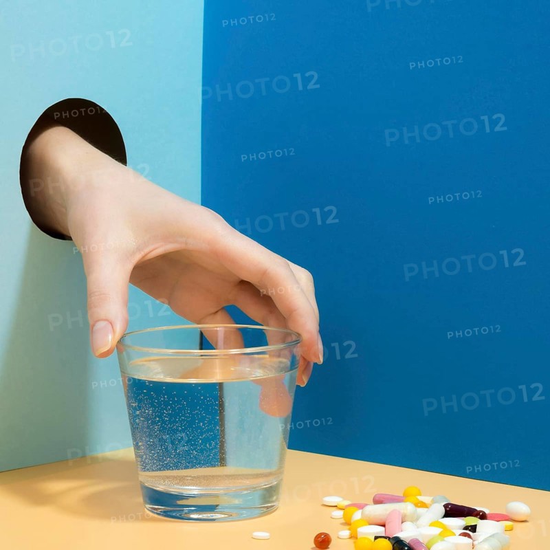 Hand grabbing glass water with pills it