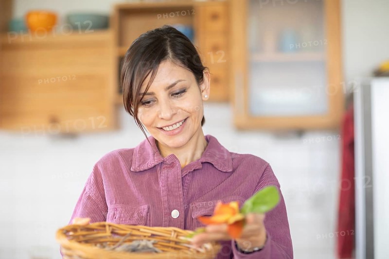 Woman in the kitchen disposes of organic waste in basket Environmental protection